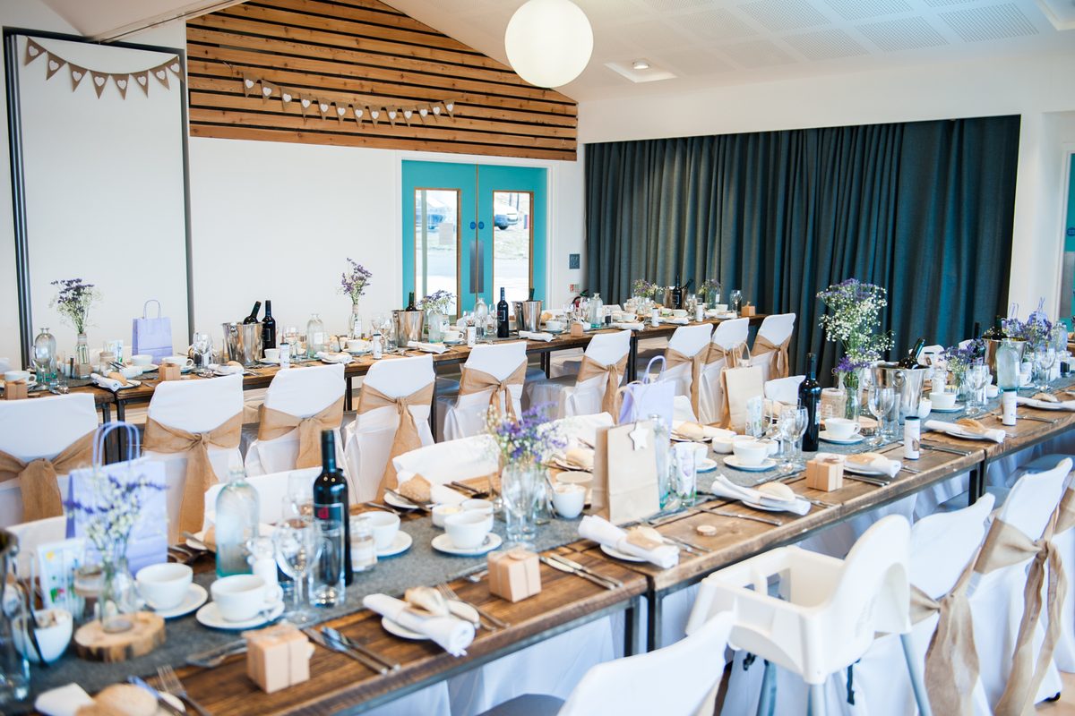Wedding reception tables set with wildflowers and bunting at Talla na Mara, Isle of Harris